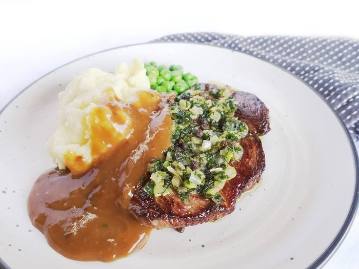Steak with creamy peppercorn sauce, garlic mash and peas