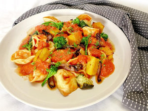 Spinach and ricotta tortellini with roasted vegetables in creamy red garlic sauce